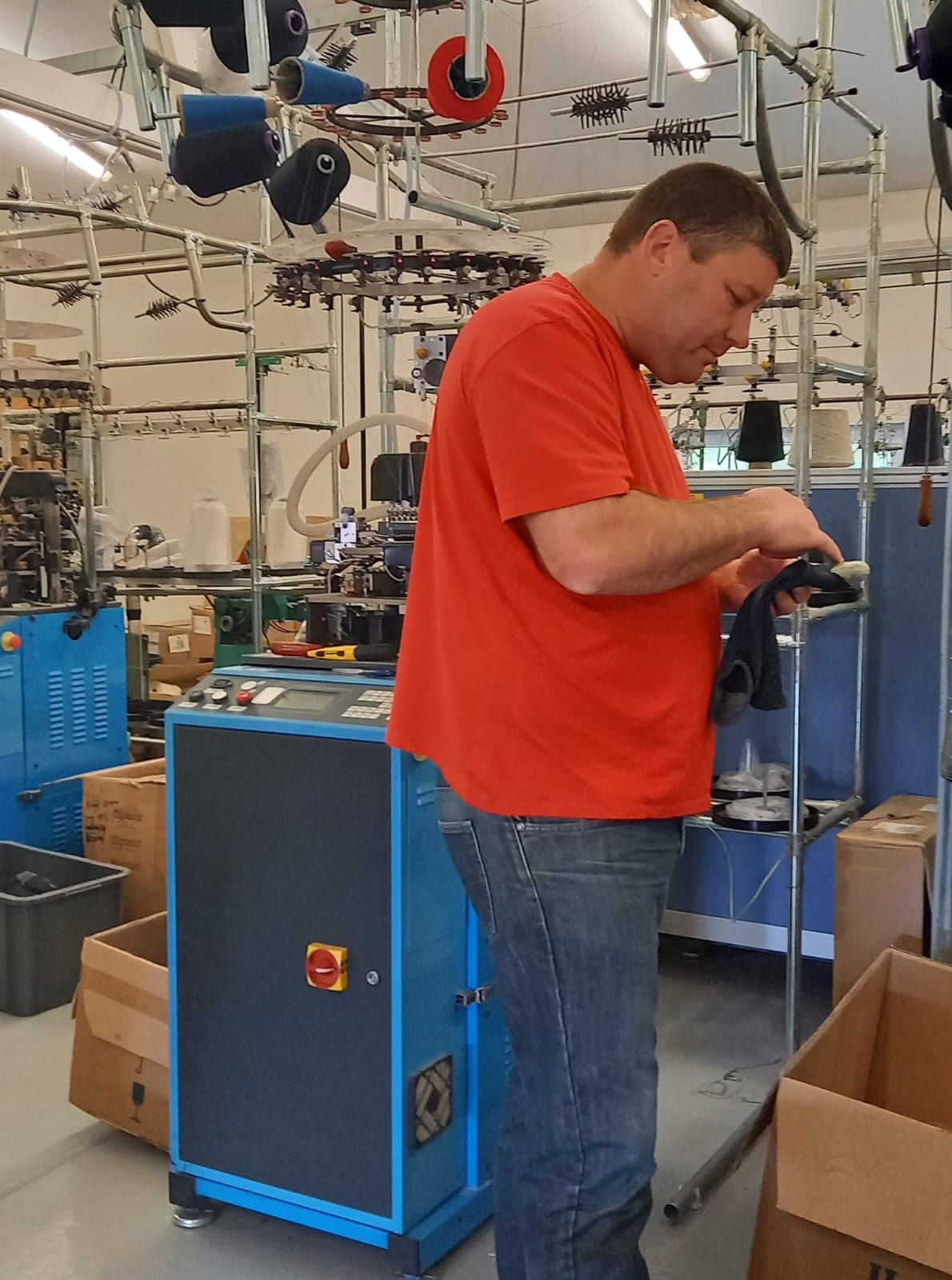 Contrôle d'une chaussette à la sortie du métier à tricoter, dans un atelier de bonneterie